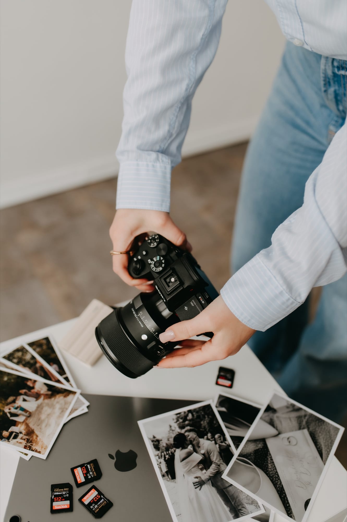 Ruce s foťákem a vytištěnými fotografiemi